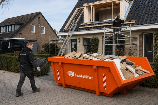 Afvalcontainer voor een woning waar een dakkapel wordt geplaatst, gevuld met hout en dakpannen