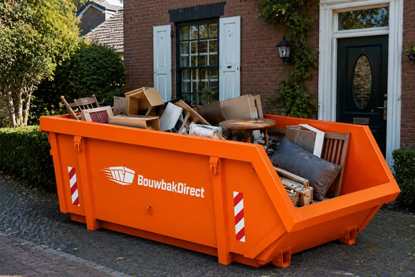Afvalcontainer voor een woning, gevuld met oude meubels en huisraad tijdens een grote opruiming